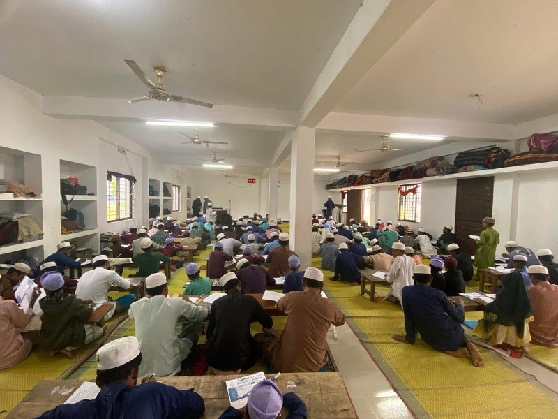 Students studying at low wooden benches in the madrasah main hall